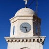 on top of the christian monastery an ancient clock with arabic numbers